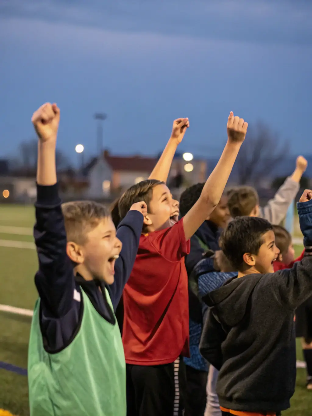 A team of teenagers, aged 13-15, in AFC Noisetiers gear, celebrating a goal during a competitive match. The image captures their excitement and camaraderie.